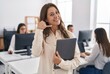 © Asier - Smiling businesswoman making a call me gesture while holding a tablet in an office