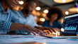 © Denis Yevtekhov - Close-up of a team reviewing financial documents spread across a conference table alongside a business intelligence dashboard on a laptop screen, defocused meeting room with soft