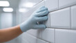 © perfectlab - Hand in glove touching white tiled wall