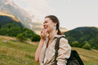 © SHOTPRIME STUDIO - A happy young woman with a backpack laughs outdoors in a mountainous landscape during daytime. She wears casual clothes and enjoys nature, representing lifestyle and adventure.