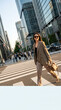 © Irvan - Stylish Asian woman walking across a busy city street at sunset, exuding confidence and sophistication