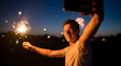 © Вадим Перегудов - Young man holding sparkler and taking selfie with smartphone at night, celebrating festive occasion with fireworks. Concept of joy, celebration, and capturing memories.