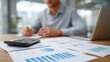 © Thares2020 - A focused individual works at a desk engaged in financial analysis and planning using documents and technology