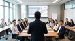 © DailyStock - Business leader standing at the head of a long wooden table giving a workshop presentation to a group of employees in a bright corporate boardroom