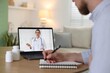 © New Africa - Telemedicine. Man having online consultation with doctor via laptop at wooden table indoors, closeup