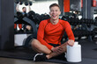 © New Africa - Happy young man with jar of protein powder in gym