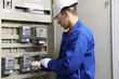 © New Africa - Electrician with screwdriver checking electrical meter indoors