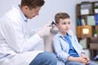© New Africa - Hearing test. Doctor examining boy's ear with otoscope in clinic
