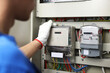 © New Africa - Electrician checking fuse box with electrical meters indoors, closeup