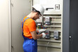 © New Africa - Electrician with screwdriver checking electrical meter indoors
