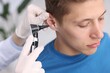 © New Africa - Hearing test. Doctor examining man's ear with otoscope in clinic, closeup