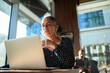 © Marko Geber - Senior woman working on laptop in modern cafe