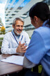 © Marko Geber - Senior doctor mentoring nurse during outdoor hospital meeting