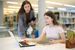 © JackF - Two girls studying for an exam together in university library using books and a laptop