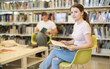 © JackF - Thoughtful woman reads books in the lecture hall. Female student is sitting in the library against the background of other students, she is looking for material for a diploma