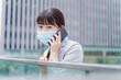 © maroke - マスクをして電話をする若いビジネスウーマン