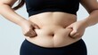 © CrazyJuke - Woman's Belly Fat: Close-up of a woman pinching her soft belly, highlighting excess fat and the desire for a slimmer physique.
