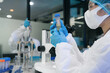© NINENII - Asian women team researchers examining natural water sample for contaminants and microplastics next to laboratory bottle.