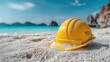© rifai_art - Yellow construction hard hat resting on a tropical sandy beach with turquoise ocean water.
