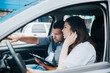 © Vlad - Male auto instructor explains driving rules to female student. Caucasian man points to the road and holds his paper. Young woman fixes her hair and listens to comments about her mistakes.