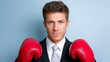 © Tetyana - Male boxer in formal suit wearing red boxing gloves poses confidently against a light blue background, showcasing a unique blend of professionalism and athleticism