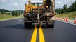 © Helen - Paving machine operating on fresh asphalt beside orange road work cones.