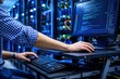 © Rosi - A man in a blue and white shirt works on a computer in a data center.