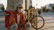 © forenna - Gig economy delivery worker crouched beside a bicycle locking station reviewing a rejected surge payment notification, depicting algorithmic income control, platform labor exploitation, on-demand wo