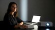© YEASIN - Woman using laptop with projector in dark office