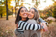 © Jelena - Two girls share a joyful hug in an autumn park filled with colorful leaves