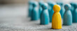 © MultiPixel - Group of wooden figures with one yellow figure standing out among blue figures in a simple setting