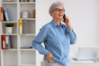 © Pixel-Shot - Happy senior businesswoman with laptop talking by mobile phone in office