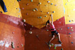 © New Africa - Athletic woman climbing wall in gym, back view. Space for text