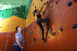© New Africa - Instructor helping woman on climbing wall in gym