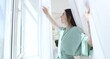 © New Africa - Smiling woman in bathrobe opening beautiful window curtains at home