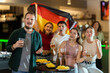 © JackF - Group of fans of Germany team with a flag are watching the match on TV in a beer bar. They are worried and supporting their