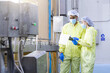 © iPoguz - Food industry inspectors in protective suits reviewing data in factory, quality assurance team wearing hygiene gear inspecting food production line, food safety auditors monitoring factory machinery