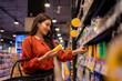 © Wasana - Woman choosing product from supermarket shelf for grocery shopping