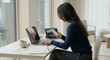 © Jai Izzam - Faceless female freelancer checking smartphone while working on laptop computer
