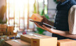 © chaylek - Entrepreneur managing online parcel orders with digital tablet and shipping workflow system, supporting e-commerce fulfillment, inventory tracking, package preparation, and retail delivery operations.