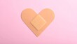 © Abdul - Top View of Heart Shaped Adhesive Bandage Plaster on Pink Background