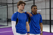 © wavebreak3 - Diverse male players standing on purple court inside wire mesh facility wearing blue shirts