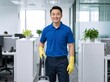 © Vasiliy - Smiling Asian male cleaner with vacuum in modern office. Professional janitor in blue polo and yellow gloves. Workplace maintenance and cleaning service