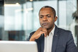 © Liubomir - Serious businessman thinking deeply and frowning while viewing information on a laptop screen, conveying contemplation, problem-solving, and focused efforts in a corporate environment