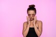 © Volodymyr_sh - Woman applying under eye patches for skincare, promoting beauty and self care on a pink background