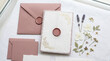 © Maryna - Elegant stationery featuring pink envelopes and a decorative wax seal, accompanied by dried flowers for a romantic touch.