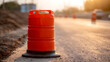 © photo for everything - Orange traffic barrel on a dusty road at sunset, shallow depth of field, bright warm light, construction safety signal