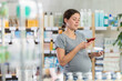 © JackF - Pregnant woman shopping at pharmacy and scanning ointment barcode on mobile phone. Modern payment methods by QR code