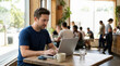 © Xenia - Focused man working remotely on a laptop in a busy cafe. Freelancer using a coffee shop as a workspace