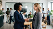 © Xenia - Diverse businesswomen shaking hands in a modern office. Professional Black and white female colleagues smiling. Workplace allyship and corporate equality concept